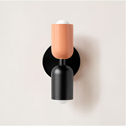 Wall light with a peach upper head and black lower head on a round black backplate. 23