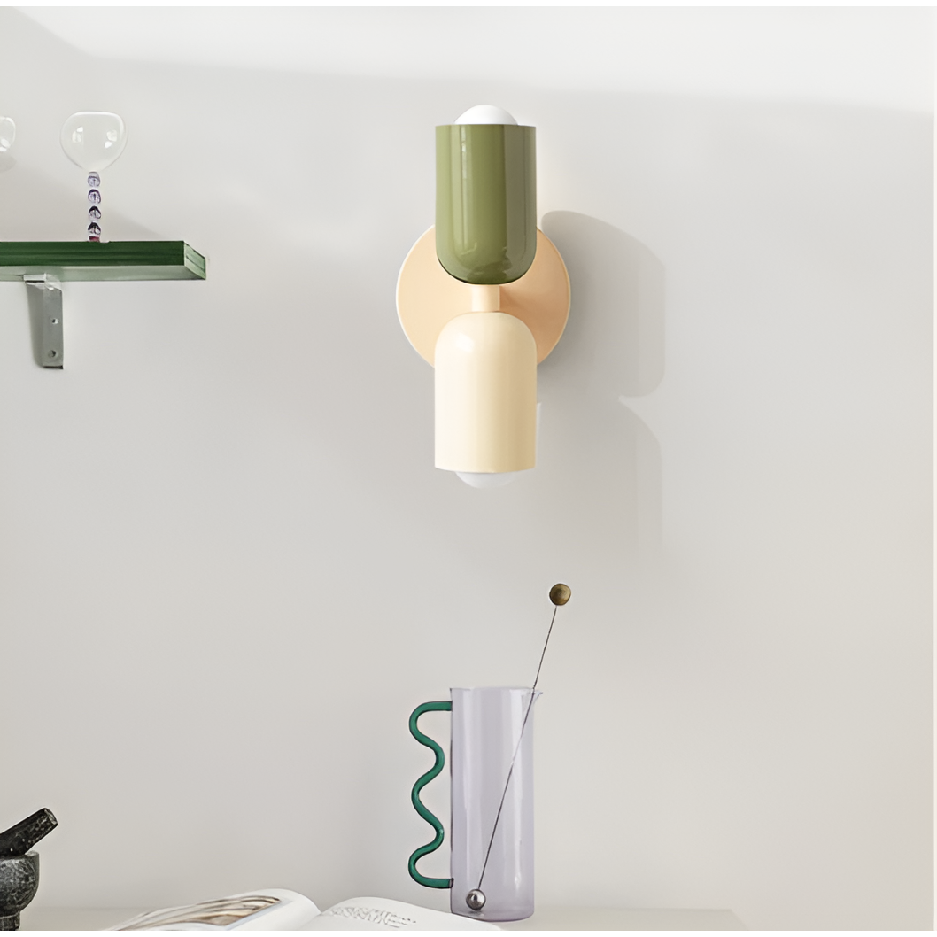 Green and cream wall light mounted in a room beside a glass shelf and a wavy-handled glass jug. 35