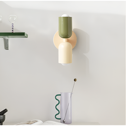 Green and cream wall light mounted in a room beside a glass shelf and a wavy-handled glass jug. 35