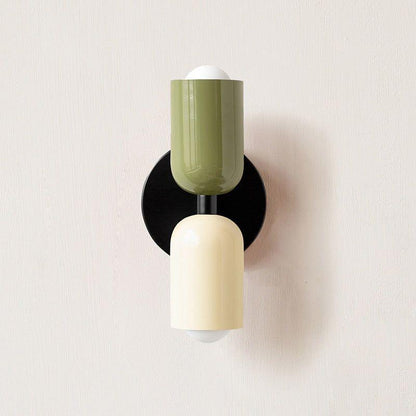 Wall light with a green upper head and cream lower head on a round black backplate, front view. 9
