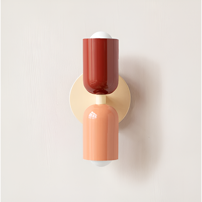 Close front view of a wall light with a red upper head and peach lower head on a cream backplate. 15