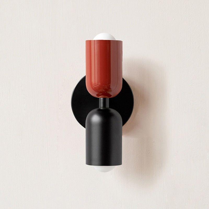 Wall light with a red upper head and matt black lower head on a round black backplate, front view. 7