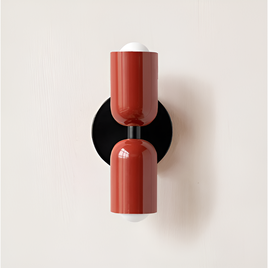 Close front view of a wall light with two red heads on a round black backplate. 19
