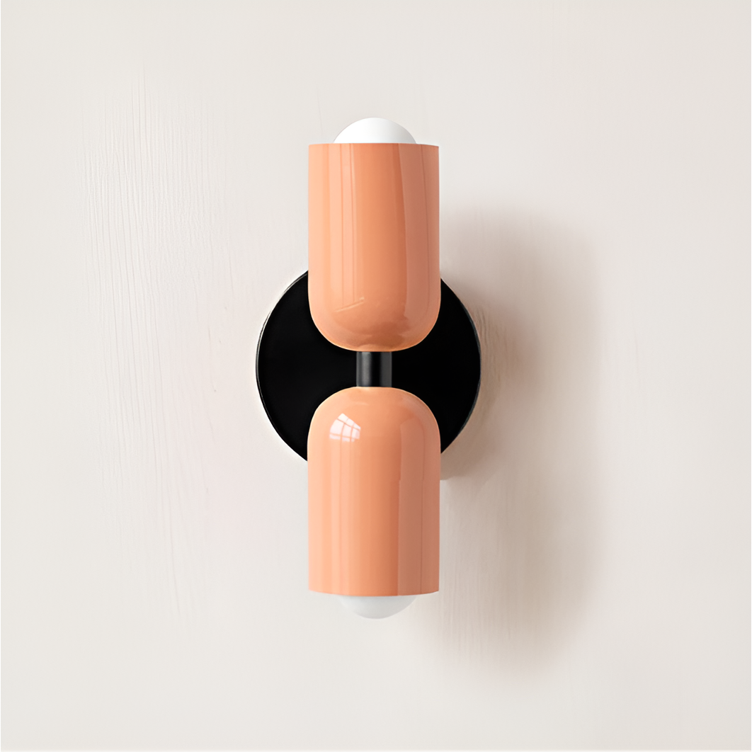 Wall light with both heads in peach on a round black backplate. 34