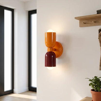 Orange and burgundy wall lamp glowing in a bright entrance hall with tall windows, a wooden coat rack and a potted plant. 11