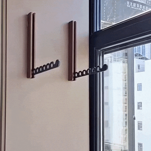 Two dark wooden racks fixed to a cream wall beside a window, each with its black perforated arm unfolded. 2