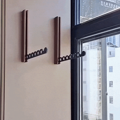 Two dark wooden racks fixed to a cream wall beside a window, each with its black perforated arm unfolded. 2