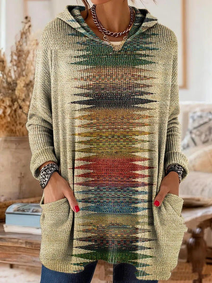 Hooded tunic in a sandy beige knit with a central band of multicoloured zigzag shapes, worn with hands in the pockets. 5