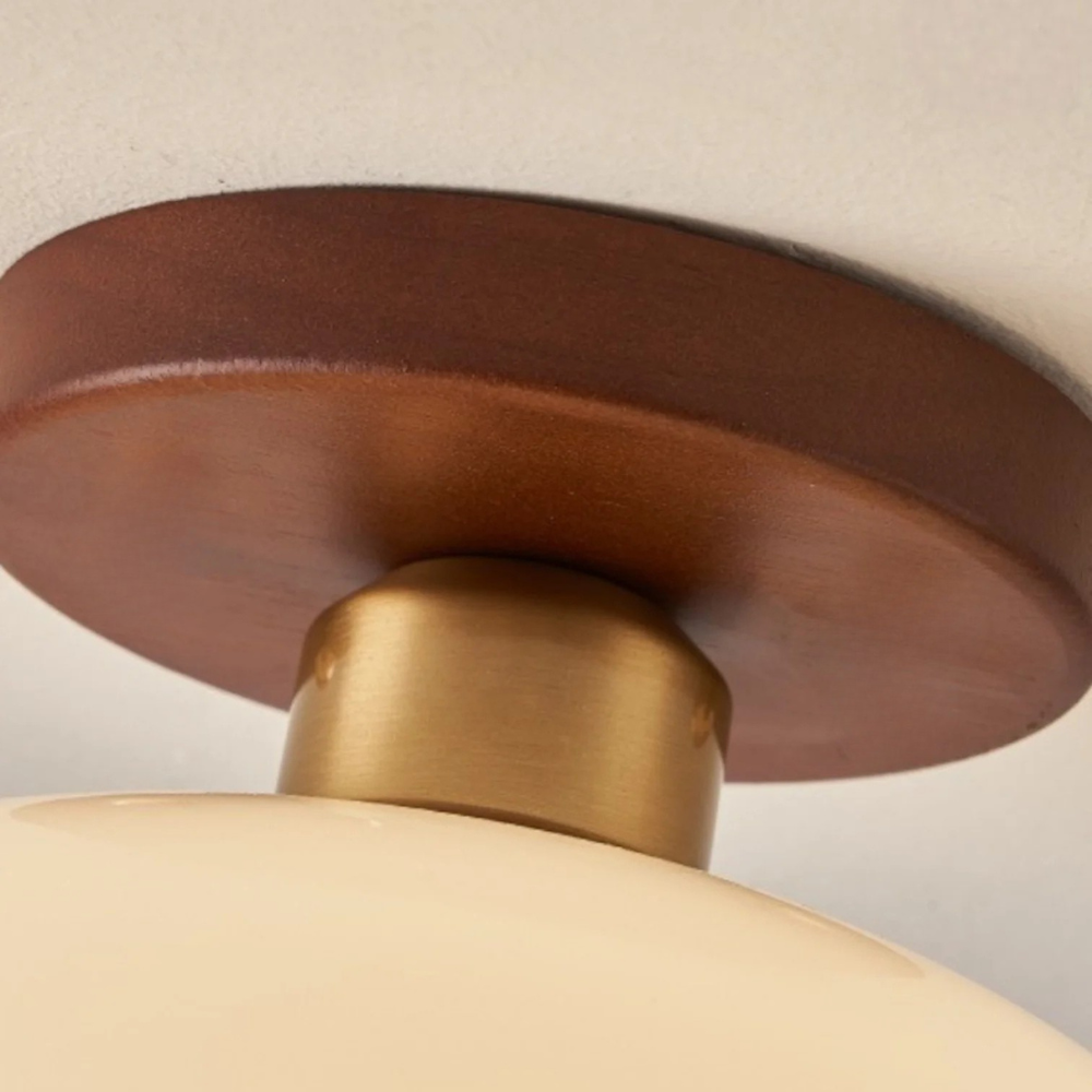 Close-up of the round wooden ceiling plate and brushed brass connector above the glass shade 5