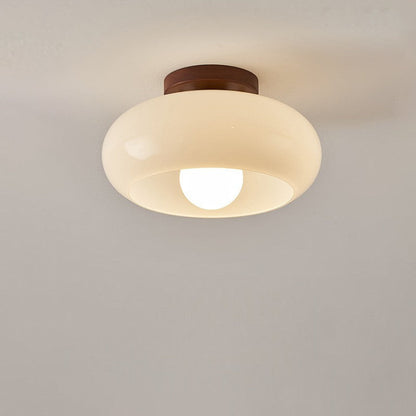 Front view of the lit glass shade with exposed round bulb against a plain ceiling 6