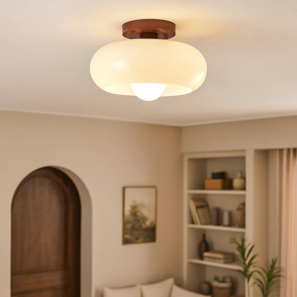 Lit cream glass ceiling light with wooden base in a cosy room with arched door 1