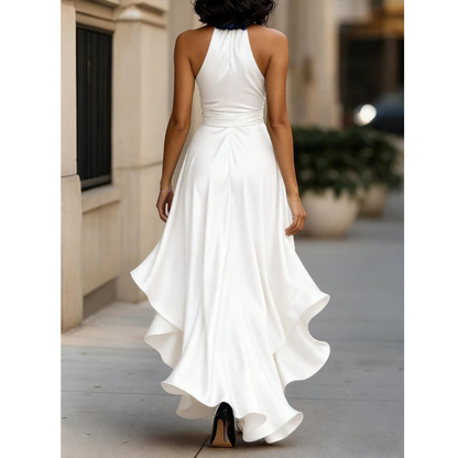 Back view on a model of the white satin halter dress, with cut-away shoulders and rippling layered hem. 10