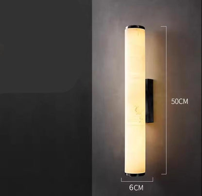 Lit cylindrical marble wall light with a dark bracket on a grey wall, with dimension lines showing height and width. 21