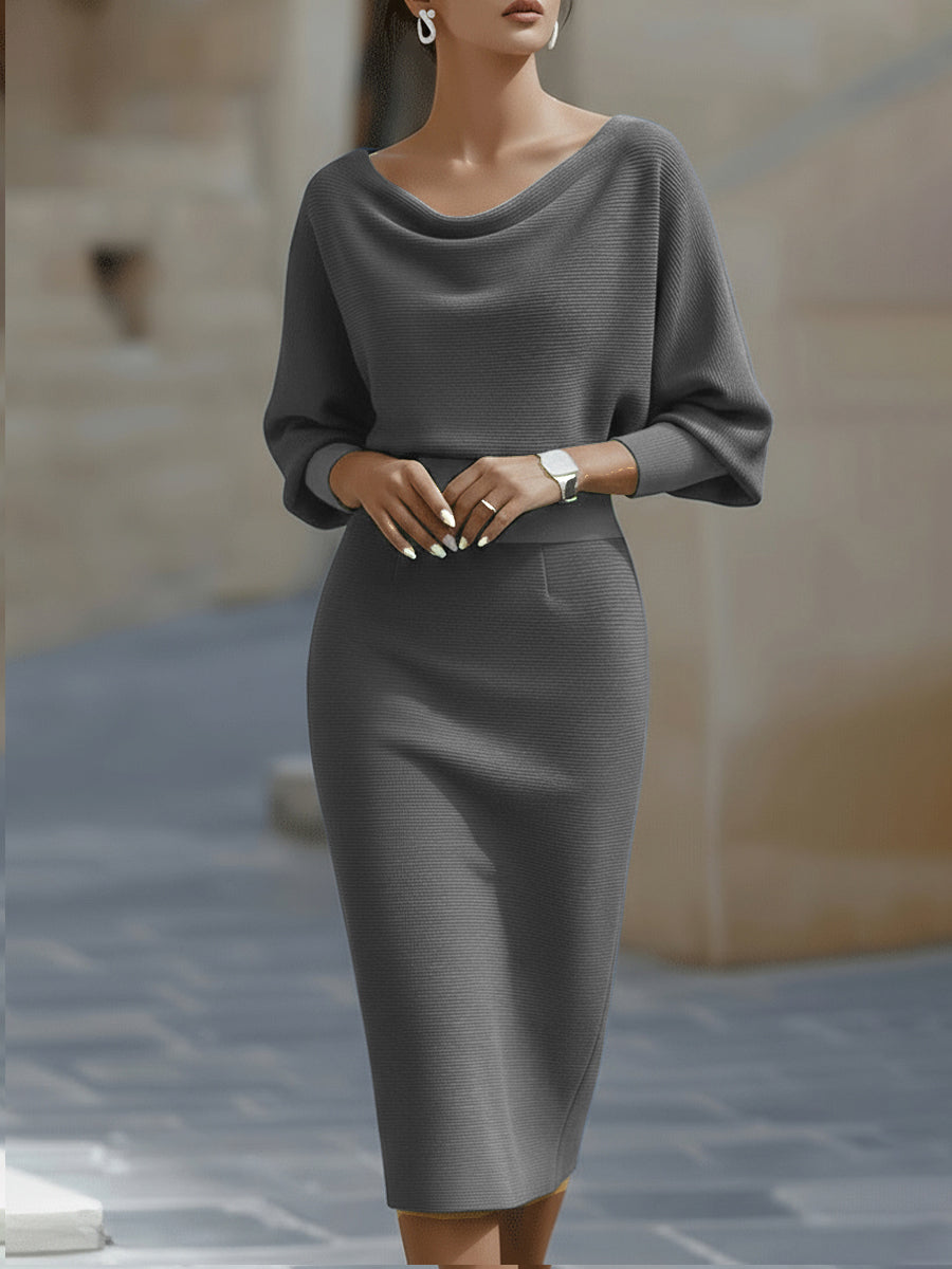 Model wearing the midi dress in grey, front view, hands clasped at the waist, showing the draped neck and wide sleeves. 5
