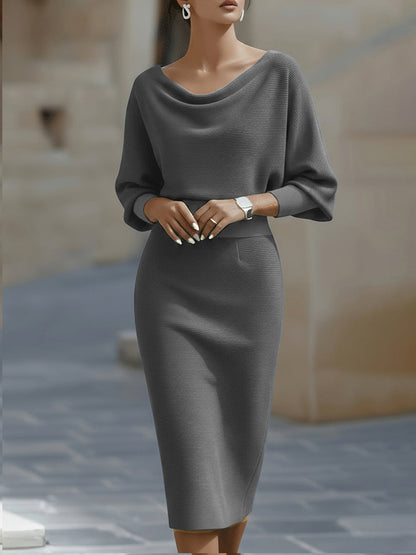 Model wearing the midi dress in grey, front view, hands clasped at the waist, showing the draped neck and wide sleeves. 5