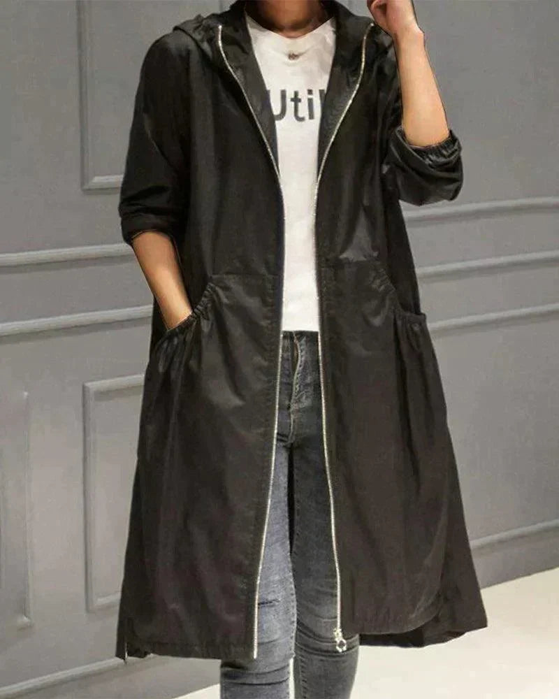 Black hooded raincoat worn open with the zip visible, over a white top and blue jeans 4