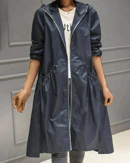 Navy blue hooded raincoat worn open with a glossy finish, showing zip edges and gathered pockets 6