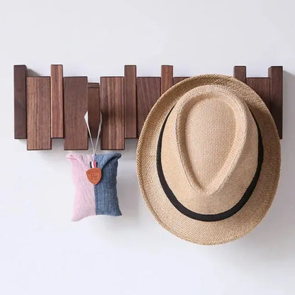 Dark wooden rack on a white wall with a straw hat and a small pink and blue pouch hanging 2