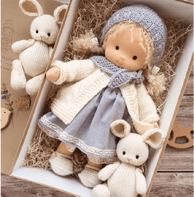 Doll in blue knitted bonnet, cream cardigan and lace-trimmed dress, boxed with two knitted bunnies 4