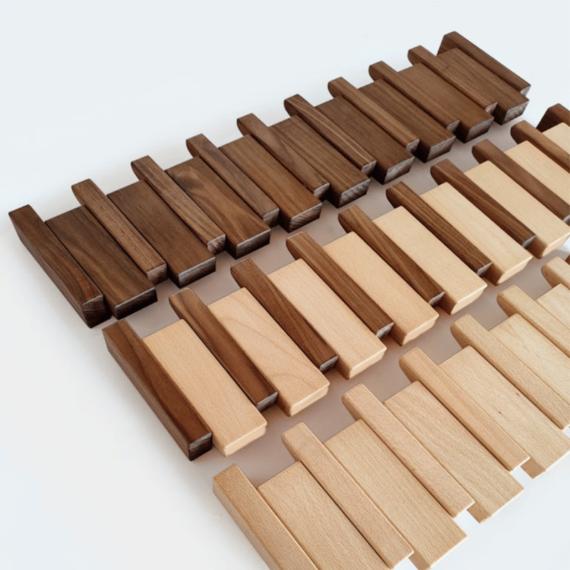 Flat lay of unassembled wooden pieces in dark walnut and pale beech tones arranged in rows 8
