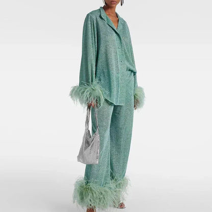 Model wearing the set in sage green glitter with a notched collar, carrying a silver mesh bag, feather trim on cuffs and hems. 2