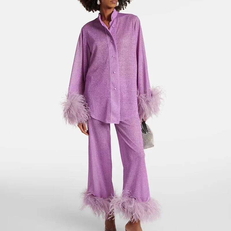 Model wearing the set in lilac glitter, a buttoned stand-collar shirt and wide trousers with pale feather trim at cuffs and hems. 3