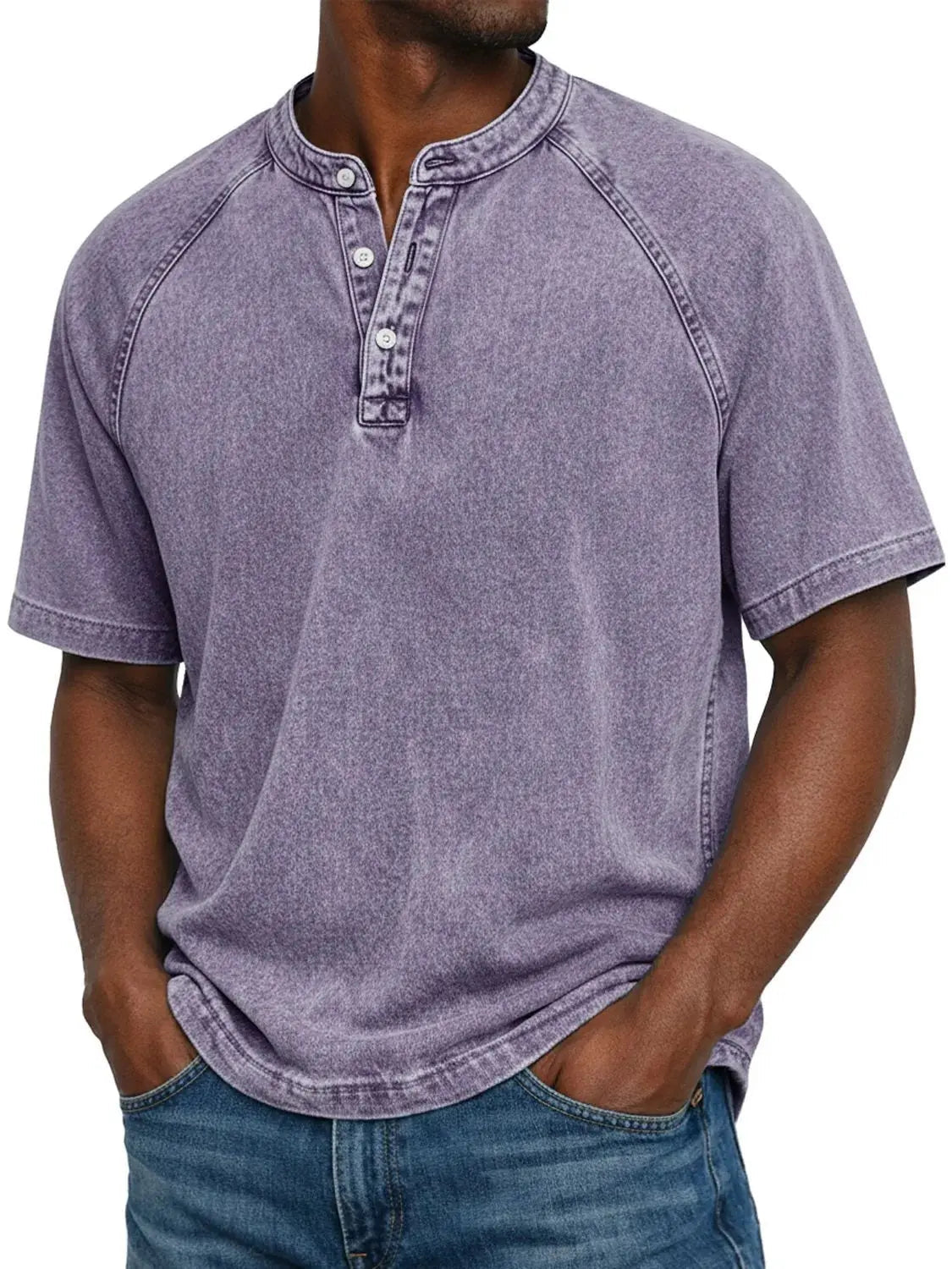 Model wearing the short-sleeved raglan Henley in a washed lavender purple, with a three-button placket, hands in jeans pockets. 1