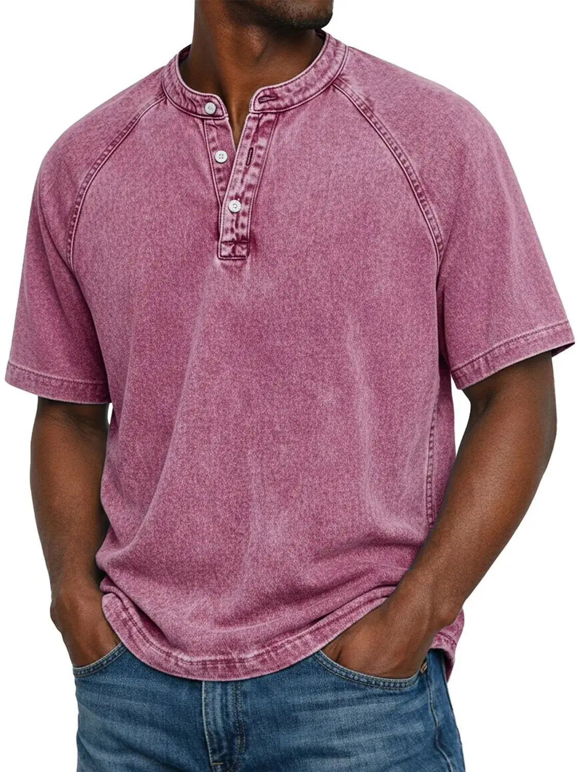Model wearing the short-sleeved raglan Henley in a washed berry pink, with a three-button placket, worn with blue jeans. 10