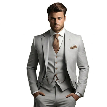 Model wearing the suit in light grey, styled with a tan textured tie, pocket square and waistcoat chain, hands in pockets. 3