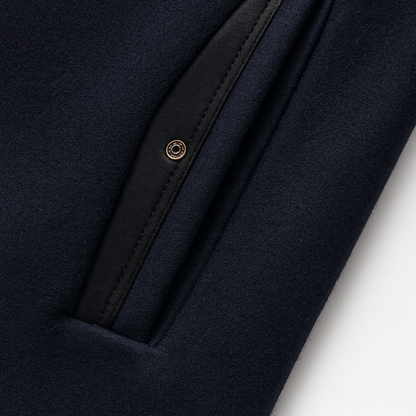 Close-up of a navy slanted pocket edged in black faux leather with a small metal snap 9