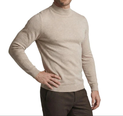 Model in a beige knit jumper with ribbed cuffs and hem, one hand on hip, with dark brown trousers 1