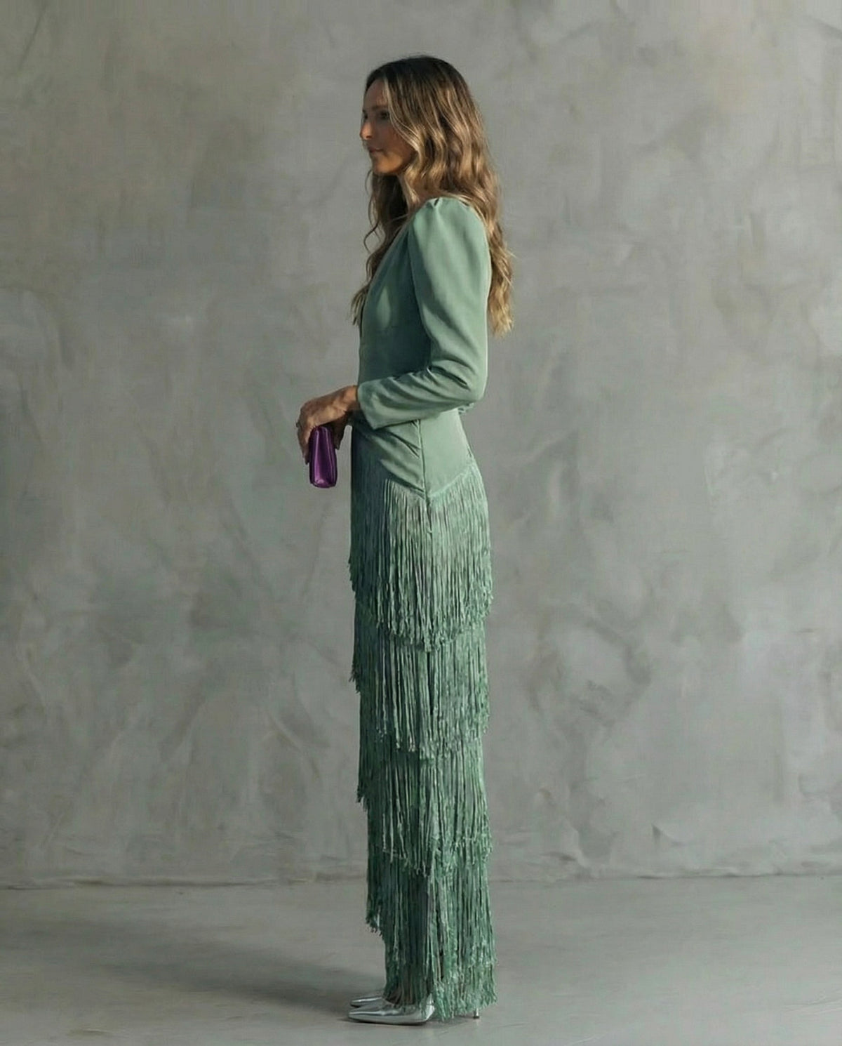 Side profile of the sage green dress, showing the cascading fringe tiers and long fitted sleeve 3