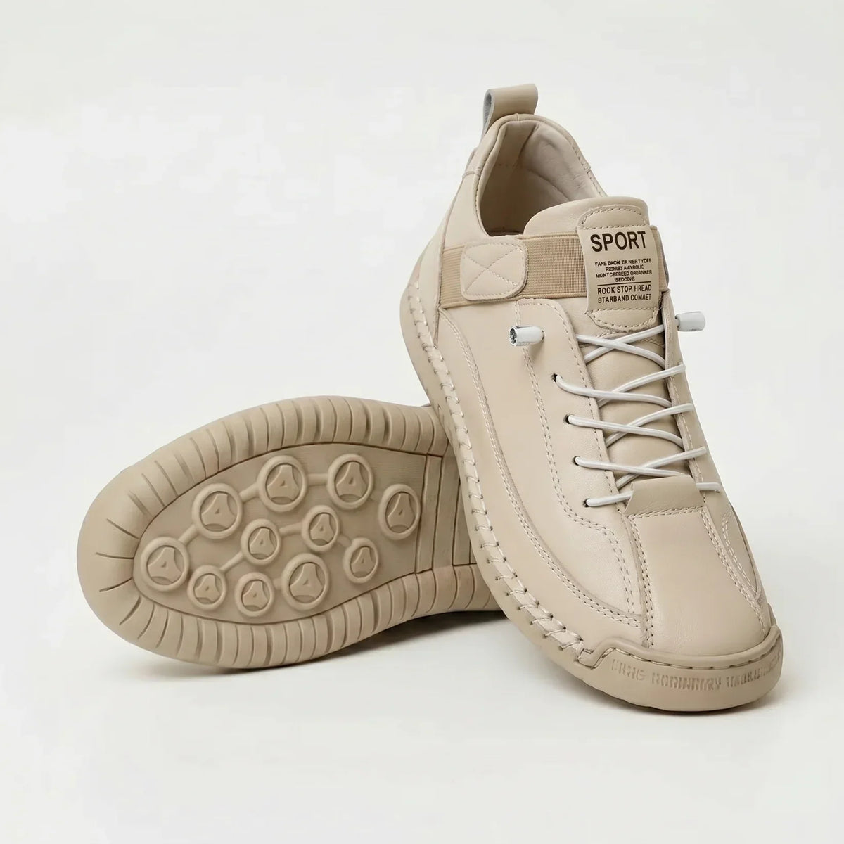 Cream leather-look trainers with white elastic laces and tonal sole, one shoe upright and the other tilted to show the studded tread. 10