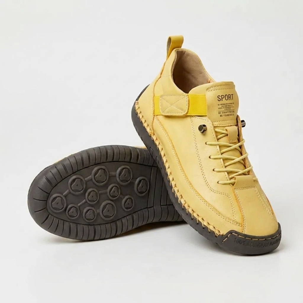 Yellow lace-up trainers with a dark grey sole and chunky stitching, one shoe upright and one on its side showing the tread. 13