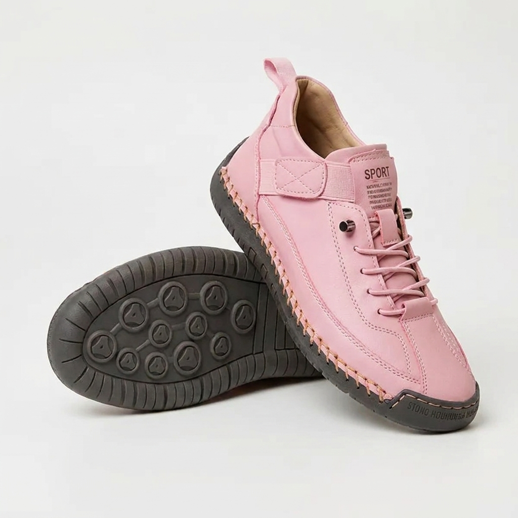 Pink lace-up trainers with a dark grey sole and orange stitching, one shoe upright and one tilted to show the studded outsole. 14