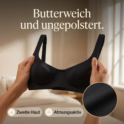 Hands holding up the black bra by its straps in a bright bedroom, with a circular close-up of the smooth fabric. 9