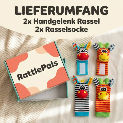 Open cardboard gift box beside the four pieces: two wrist rattles with fastening patches and two foot socks, zebra and giraffe designs. 6