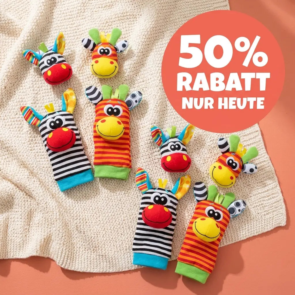 Zebra and giraffe wrist rattles and striped foot socks arranged in two sets on a cream knitted blanket against a coral background. 8