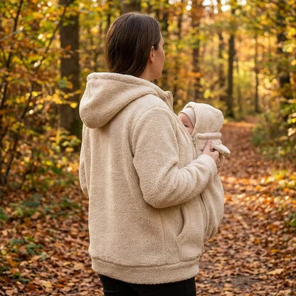 Back and side view of a woman in a cream sherpa hoodie in autumn woods, baby snug in the front panel. 6