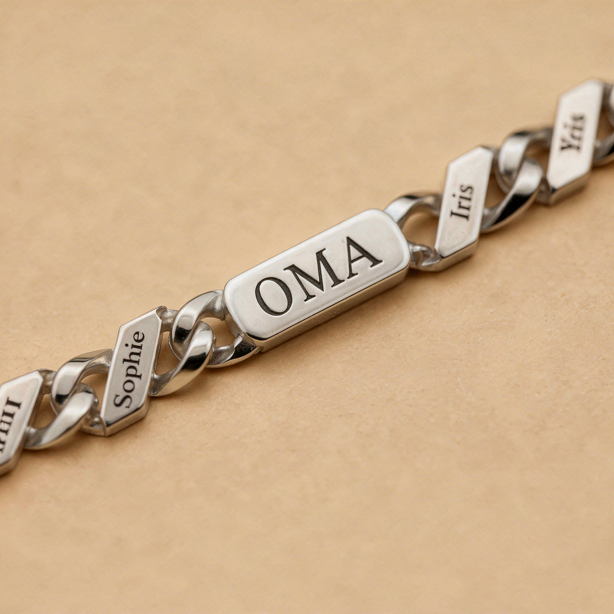 Close-up of the silver chain's engraved central bar and neighbouring name links, showing the crisp black lettering on polished metal. 8