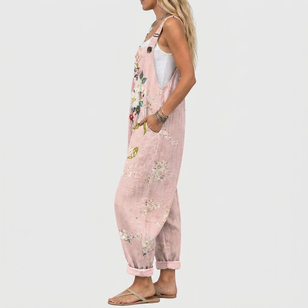 Side view of the overalls on a model, showing the wide-leg shape, rolled hems, strap button and hand resting in a pocket. 3