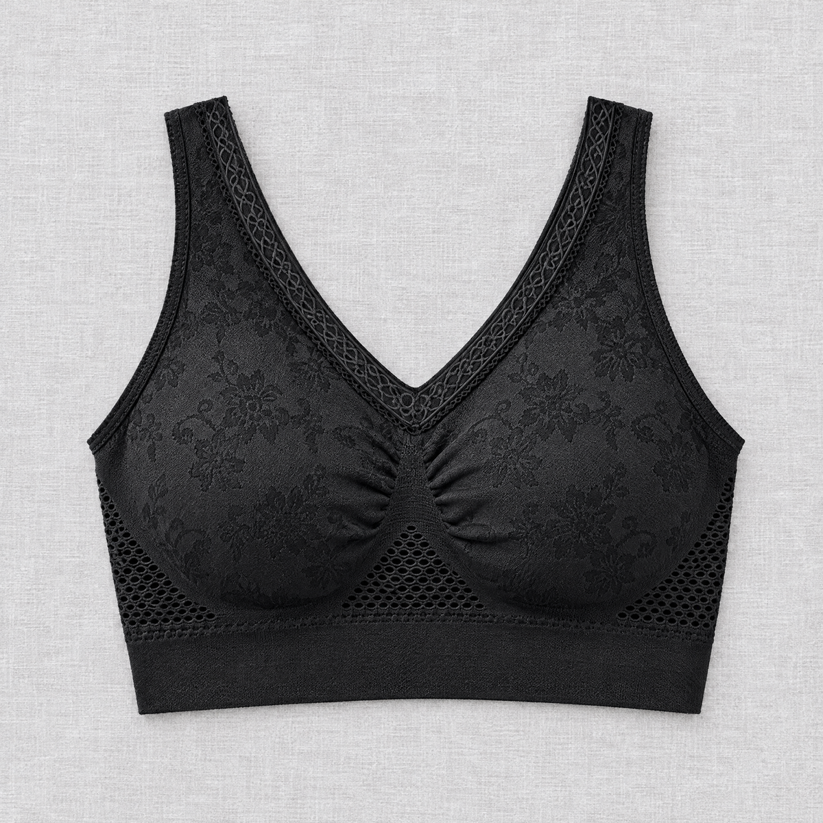 Black bra laid flat from the front, showing floral jacquard fabric, lace-edged V-neck, ruched centre and mesh panels 3