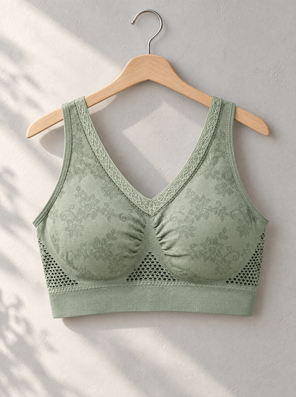Green bra hanging on a wooden hanger against a light wall, with sunlight and shadows falling across it 4