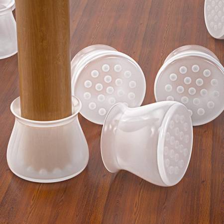 Clear silicone caps on a wooden floor, one fitted to a table leg and others upturned to show the dotted grip bases. 2
