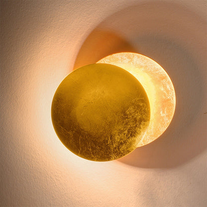 Close-up of the gold-leaf front disc overlapping a softly glowing disc on a textured wall 11