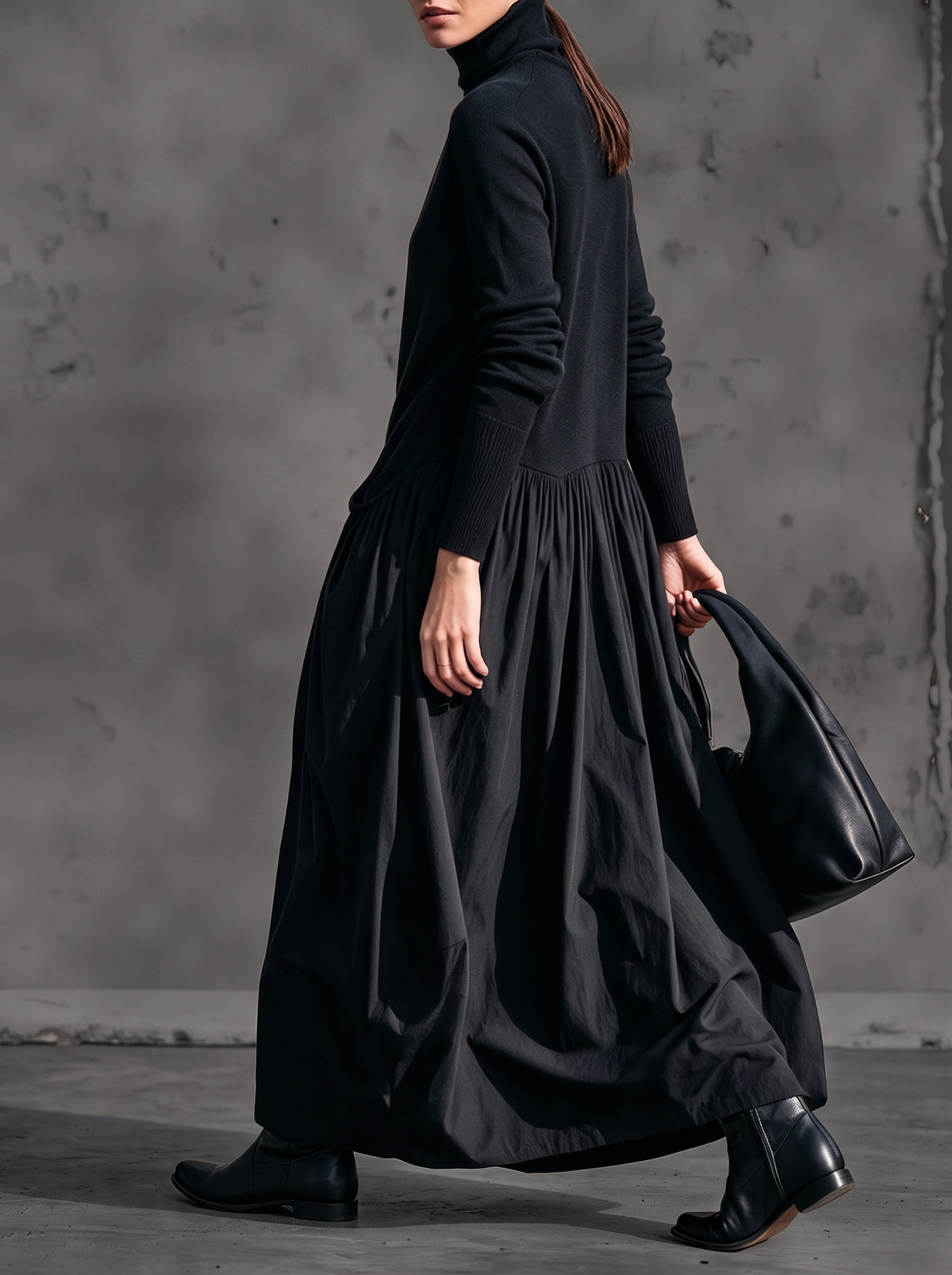 Black maxi dress worn by a model walking, shown in side view with the gathered waist seam 2
