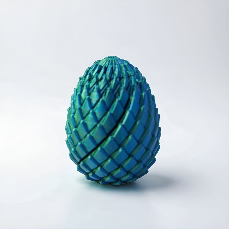 Closed egg with teal and green scales and a metallic sheen, standing against a plain pale background. 11