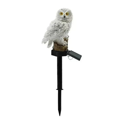 White owl solar light on its black ground stake with the folding solar panel angled out, on a plain background. 15