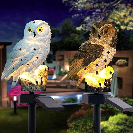 White owl and brown owl solar lights side by side, both glowing warmly on stakes in a garden at night. 17