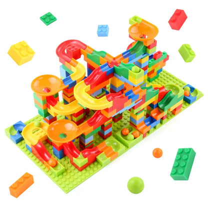 Assembled colourful plastic marble run on a green baseplate, with loose bricks and small balls scattered around it on white. 1